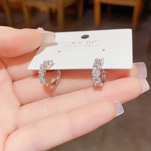 Macro shot of silver-toned hoop earrings with cubic zirconia on white display card