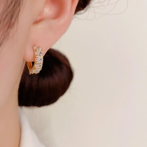 Close-up of elegant gold hoop earrings with sparkling cubic zirconia on a female model