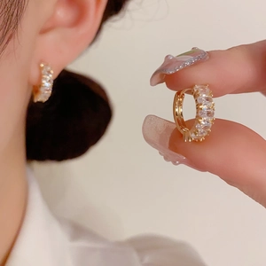 Detailed macro view of gold-plated huggie earrings with sparkling cubic zirconia inlay