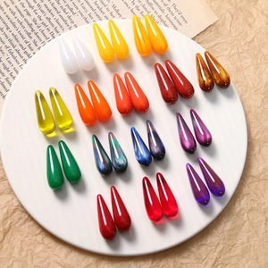 Macro view of colorful resin teardrop charms with marble texture on ceramic plate