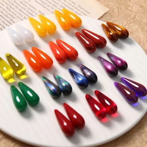 Close-up of colorful resin teardrop beads for DIY jewelry making on vintage paper