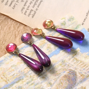 Macro detail of teardrop resin charms with purple sand star effect and golden metal loops