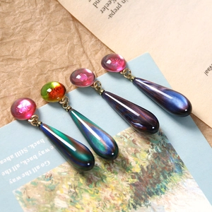 Macro detail of long teardrop resin pendants with vintage colorful starry sand patterns