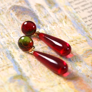 Detail of vintage style resin drop earrings with translucent red beads and gold metal links