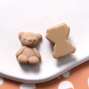 Macro detail of matte brown resin bear charms with flat back for DIY crafts