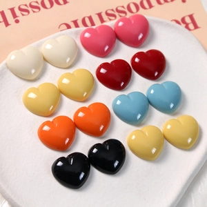 Close-up of colorful glossy resin heart charms in a white ceramic dish for DIY crafts