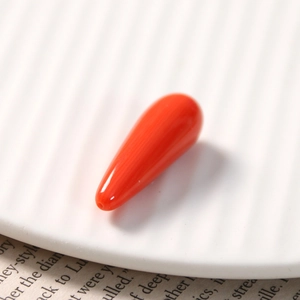 Macro shot of an orange teardrop resin charm for DIY jewelry with pre-drilled hole