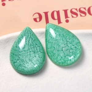 Macro shot of green water-drop resin charms with smoke crackle texture for DIY jewelry