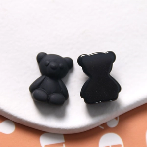 Macro shot of matte black resin bear charms showing front texture and smooth back finish
