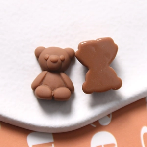 Macro view of brown resin bear charms for DIY crafts showing front and flat back details