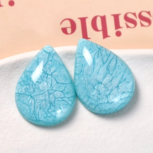 Macro detail of sky blue waterdrop resin charms with pearlescent crackle texture effect