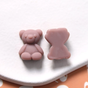 Detail of matte resin cartoon bear charms showing front relief and flat back texture
