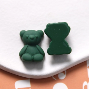 Macro detail of matte dark green resin bear charm showing front relief and flat back