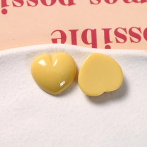 Close-up of yellow resin heart charms on a ceramic plate for DIY jewelry making