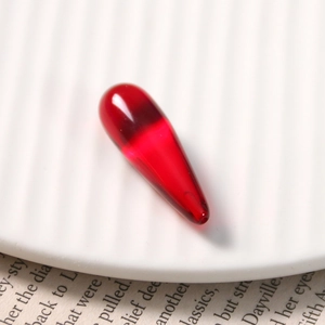 Macro shot of a translucent red teardrop resin bead with a smooth polished surface