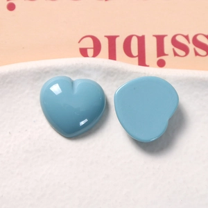 Close-up of blue resin heart charms for DIY jewelry and hair accessories on a white tray