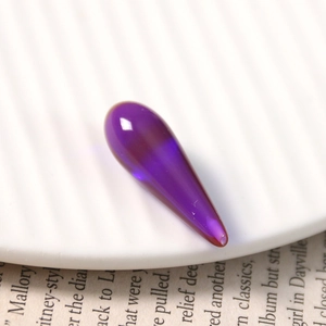 Macro detail of a purple teardrop resin bead with starry sand texture for DIY jewelry making