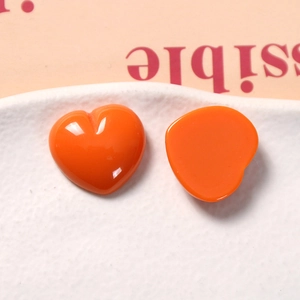 Close-up of glossy orange heart-shaped resin charms for DIY earrings and crafts