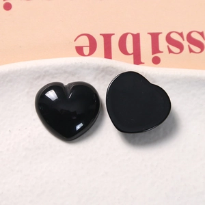 Close-up of polished black resin heart charms with flat back for DIY jewelry making