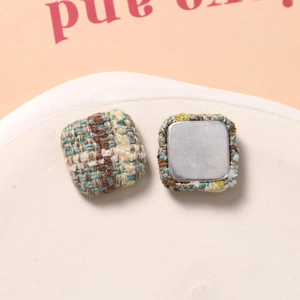 Makroaufnahme quadratischer Tweed-Knöpfe mit blauem und beige Garn für DIY-Bastelarbeiten