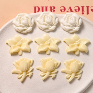Macro shot of ivory resin flower charms including roses and lilies for DIY craft projects