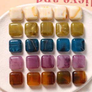 Detalle macro de cuentas cuadradas de resina jaspeada en varios colores para joyería DIY