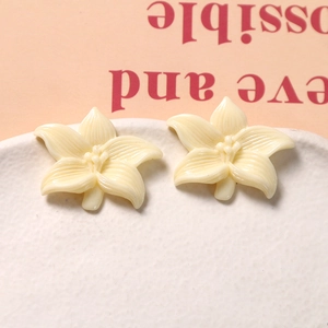Detailed close-up of cream resin daisy charms with delicate petal texture and bead centers