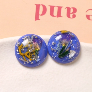 Vista macro di ciondolo in resina blu con fiori essiccati e foglia d'argento