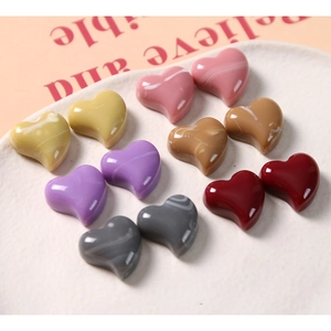 Detailed view of colorful marble patterned heart resin beads arranged in a tray