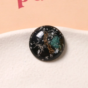 Vista macro di un ciondolo tondo in resina con foglia d'argento e catena dorata