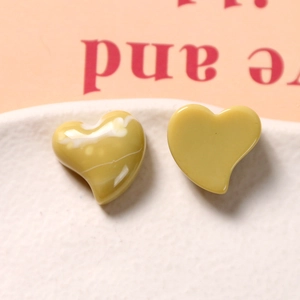 Macro shot of glossy mustard yellow resin heart accessories with marble texture details
