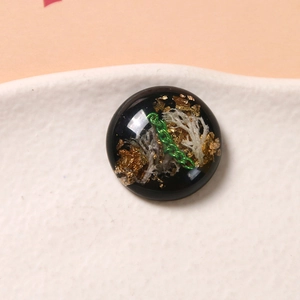 Dettaglio di un cabochon a semisfera in resina con foglia d'oro e catena per gioielli DIY