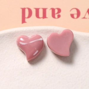 Macro view of glossy pink resin heart charms with a smooth polished finish on white ceramic