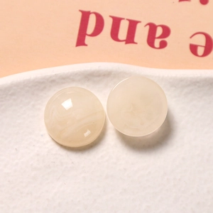 Makro-Detail von runden beige Harz-Anhängern mit Tusche-Textur für DIY-Basteln und Schmuck