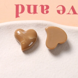 Close-up of heart-shaped caramel resin charms with white marble texture on a tray