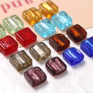 Makroaufnahme bunter durchscheinender quadratischer Glasperlen mit Goldfolie für DIY