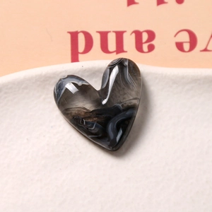 Détail macro d'une breloque en résine en forme de cœur avec texture marbrée noire et blanche