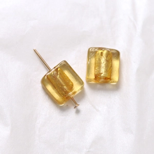 Makroaufnahme quadratischer bernsteinfarbener Glasperlen mit Goldfolie für DIY-Schmuck