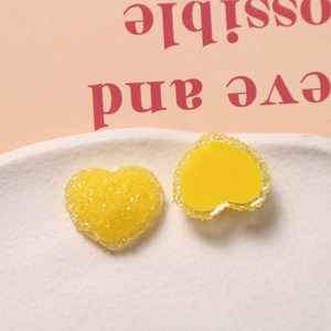 Makro-Detail gelber Herz-Harzanhänger mit Glitzertextur und flacher Rückseite für DIY-Basteln