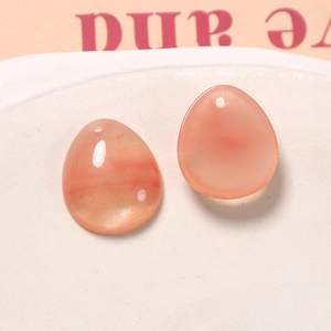 Makroaufnahme von durchscheinenden rosa-orangen Tropfen-Anhängern für DIY-Ohrringe und Schmuck