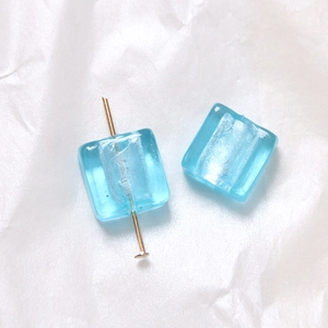 Nahaufnahme hellblauer quadratischer Glasperlen mit Silberfolie für DIY-Schmuckherstellung