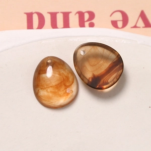 Nahaufnahme von bernsteinfarbenen Harzanhängern mit Tintenwaschtextur für DIY-Schmuck