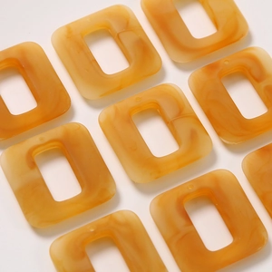 Macro view of rectangular amber acetate pendant charms with marble texture for jewelry DIY