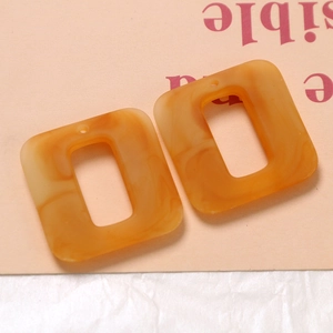 Detail of orange marble textured resin rectangle charms with pre-drilled holes for DIY
