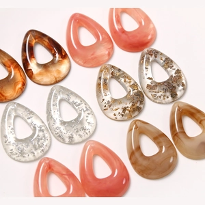 Macro detail of geometric teardrop resin charms with gold foil and marble texture for DIY jewelry