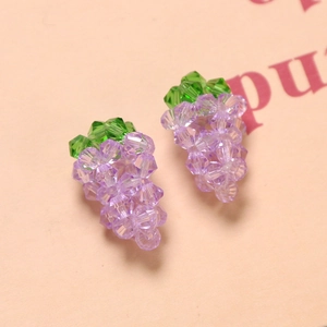 Macro detail of purple crystal grape earrings with green leaf beads and multifaceted shine