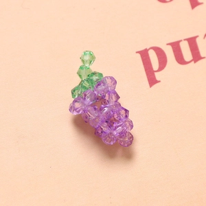 Macro shot of 3D crystal grape bead charms made with purple and green faceted acrylic beads