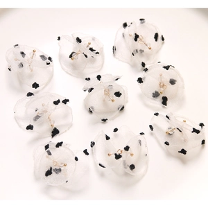 Close-up of DIY black polka dot tulle flower charms with gold bead center for accessories