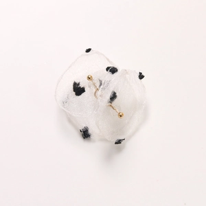 Macro detail of elegant black polka dot mesh flower earrings with gold bead accents