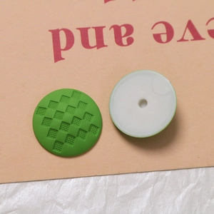 Makro-Detail grüner Silikonkappen mit Karomuster-Textur und weißem Befestigungsloch hinten